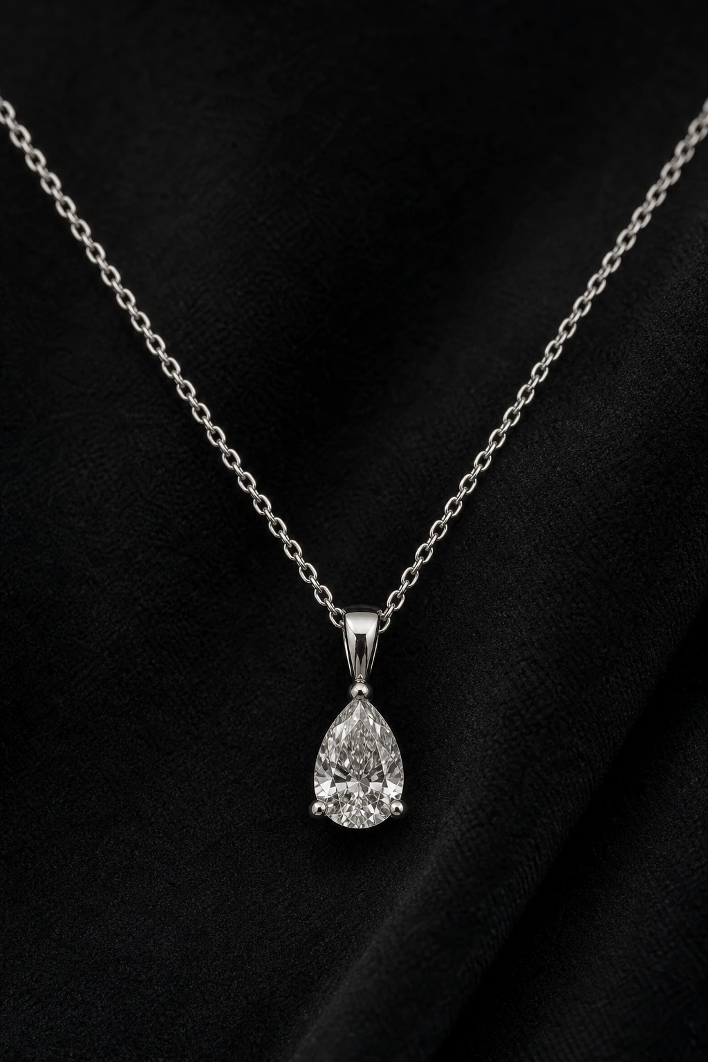 White-gold pear-shaped diamond pendant photographed on black velvet